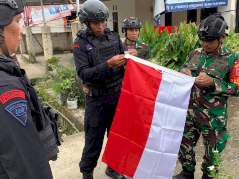 Batalyon C Pelopor Satbrimob Polda Sulsel bersama Kodim 1407 Bone membantu masyarakat memasang bendera merah putih.(Foto:IST)
