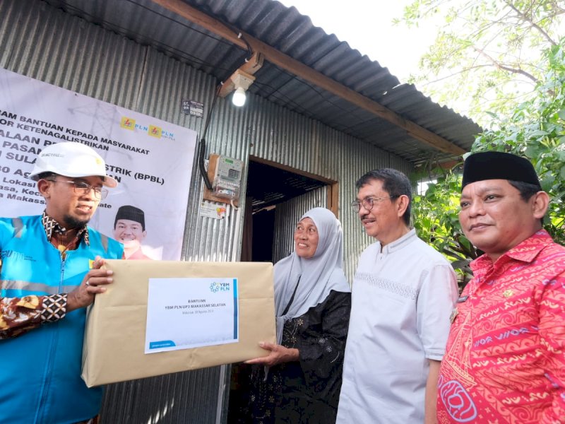 General Manager PT PLN (Persero) UID Sulselrabar, Budiono (kiri) tengah menyerahkan bantuan sembako dari YBM PLN kepada salah seorang penerima manfaat BPBL, Tasinong di Kota Makassar. (Foto: IST)