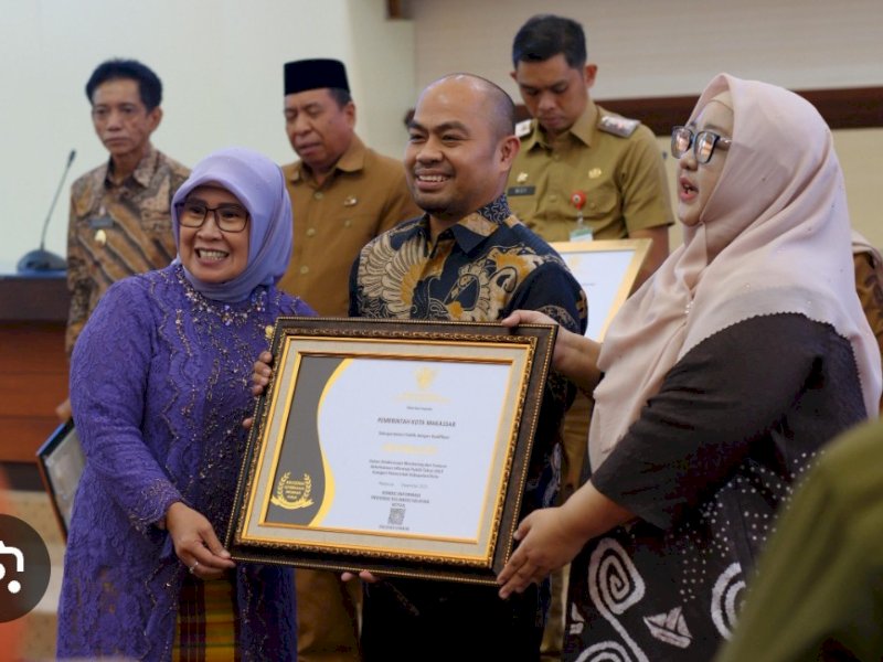 Kediskominfo Makassar, Muhammad Roem menerima plakat Anugerah Keterbukaan Informasi Publik 2025.