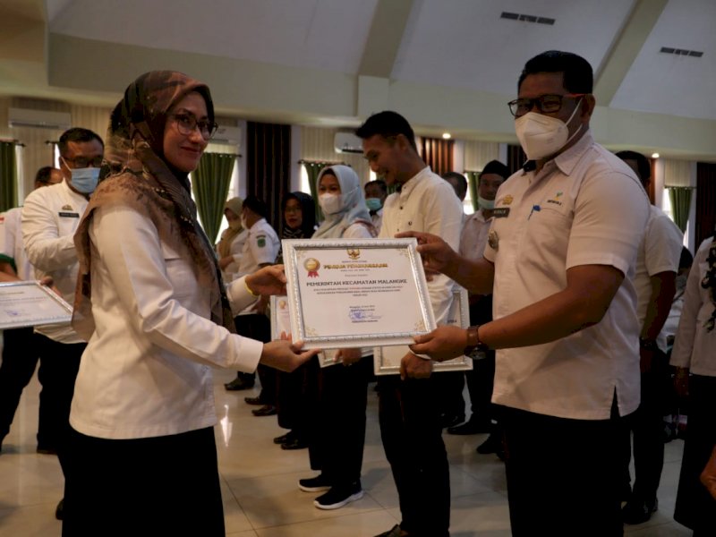 Bupati Luwu Utara Indah Putri Indriani menyerahkan penghargaan kepada Camat Malangke, Rabu (22/6/2022).