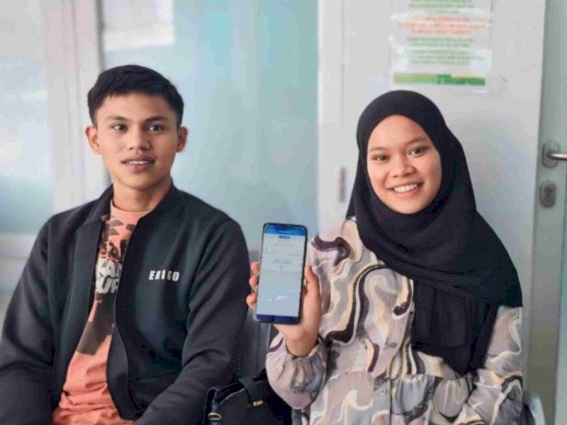 Hijrah didampingi suami menceritakan manfaat antrean online lelalui aplikasi mobile JKN