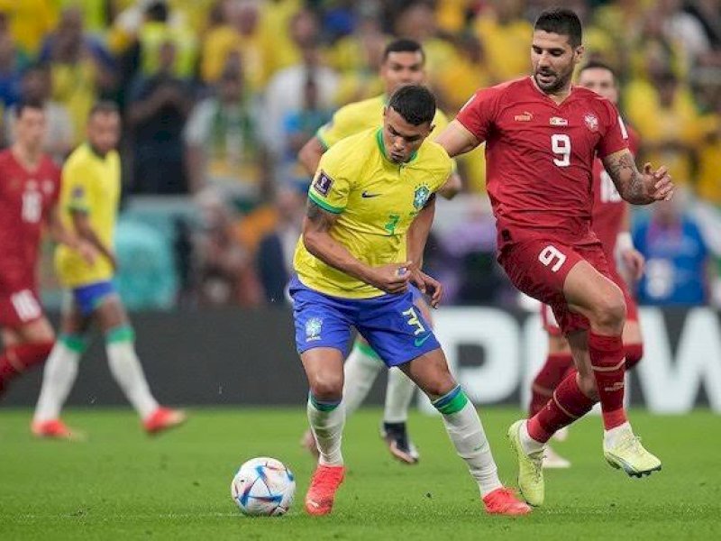Pemain Brasil mendrible bole melewati pemain Serbia. 