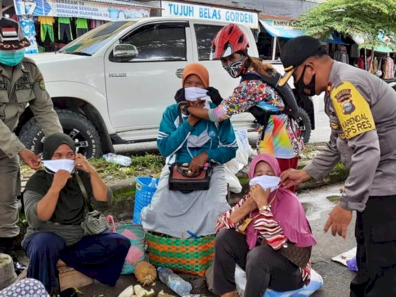 TNI/Polri membagikan masker kepada pengunjung pasar di Lutra. 