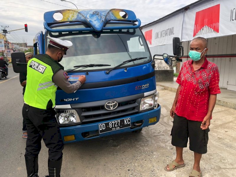 Personel Satlantas Polres Wajo saat memasangkan stiker ke kendaraan pengguna jalan. 