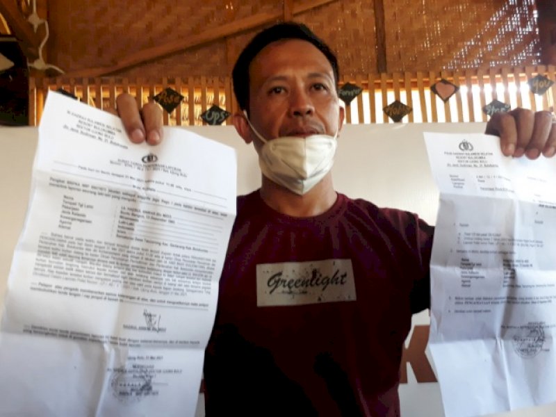 Korban memperlihatkan bukti laporan polisi. 