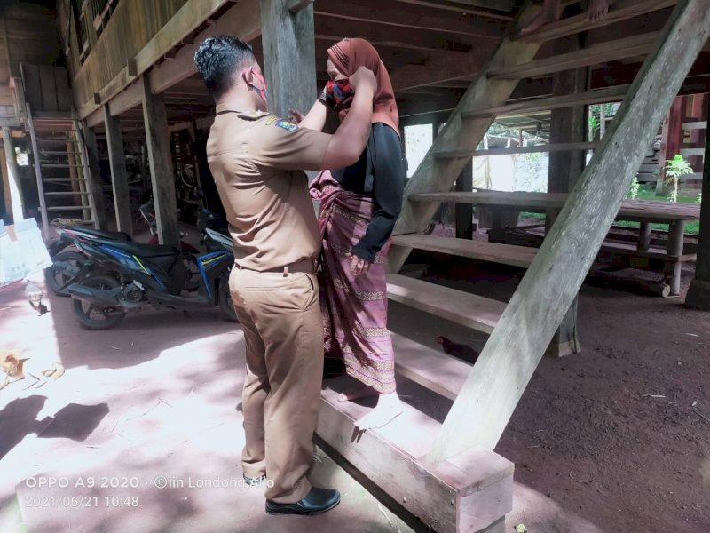 Plt Ketua APDESI Tator saat memakaikan masker warganya. 