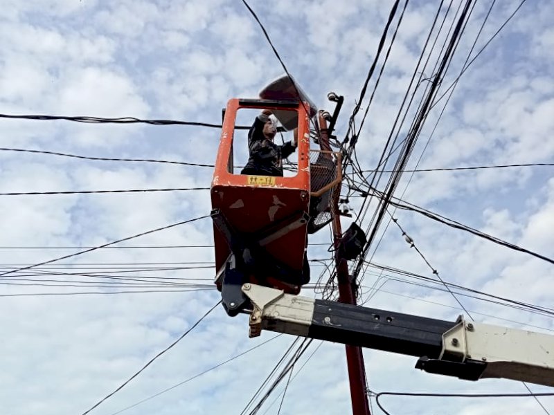Petugas UPT Lampu Jalan Dinas PU Makassar saat memperbaiki lampu jalan. 