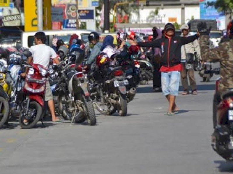 Jukir mengarahkan pengendara yang tengah mencari area parkir, di Kota Makassar. 
