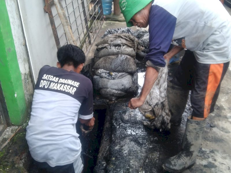 Laskar Pelangi Operasional Dinas PU Makassar melakukan pengerukan drainase. 