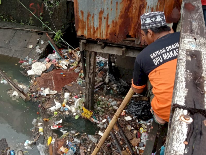Satgas DPU Makassar melakukan pembersihan saluran air.
