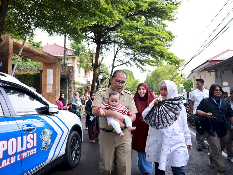 Wali Kota Makassar Moh Ramdhan Pomanto berjalan menuju TPS sambil menggendong cucunya. 