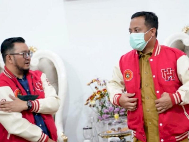 Ketua panitia pelaksana pelantikan IKA Unhas, Irwan Ade Saputra memberikan jaket seragam pengurus kepada Gubernur Sulsel, Andi Sudirman Sulaiman. (Ist)